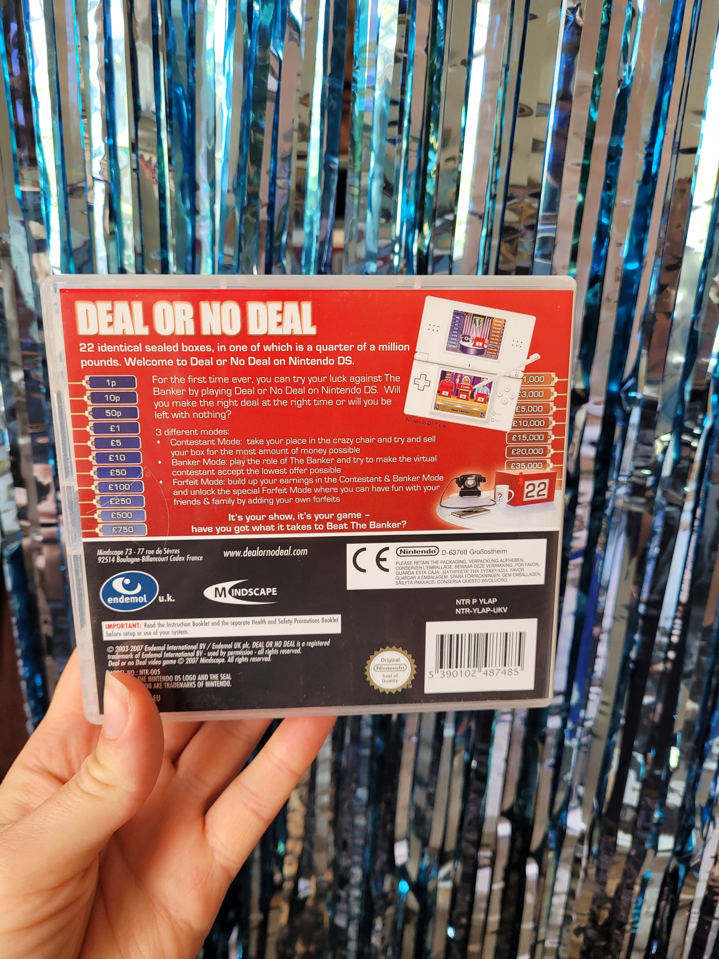 Back of the Nintendo DS game box with the blue and red prize figures up either side. The top reads '22 indentical sealed boxes, in one of which is a quarter of a million pounds. Welcome to Deal or No Deal on Nintendo DS'