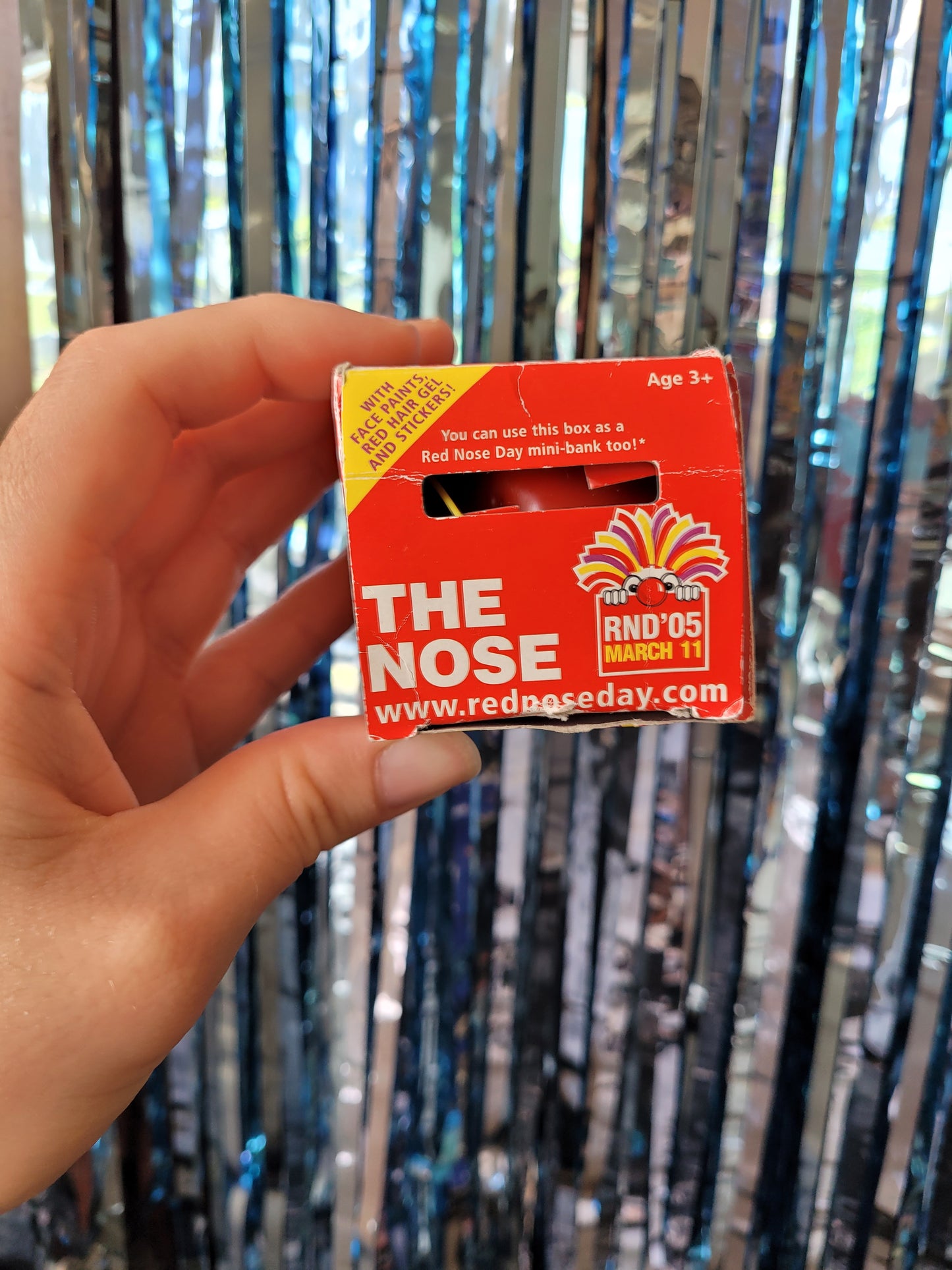 Top of the box with a coin slot. Reads 'you can use this box as a Red Nose Day mini-bank too!'