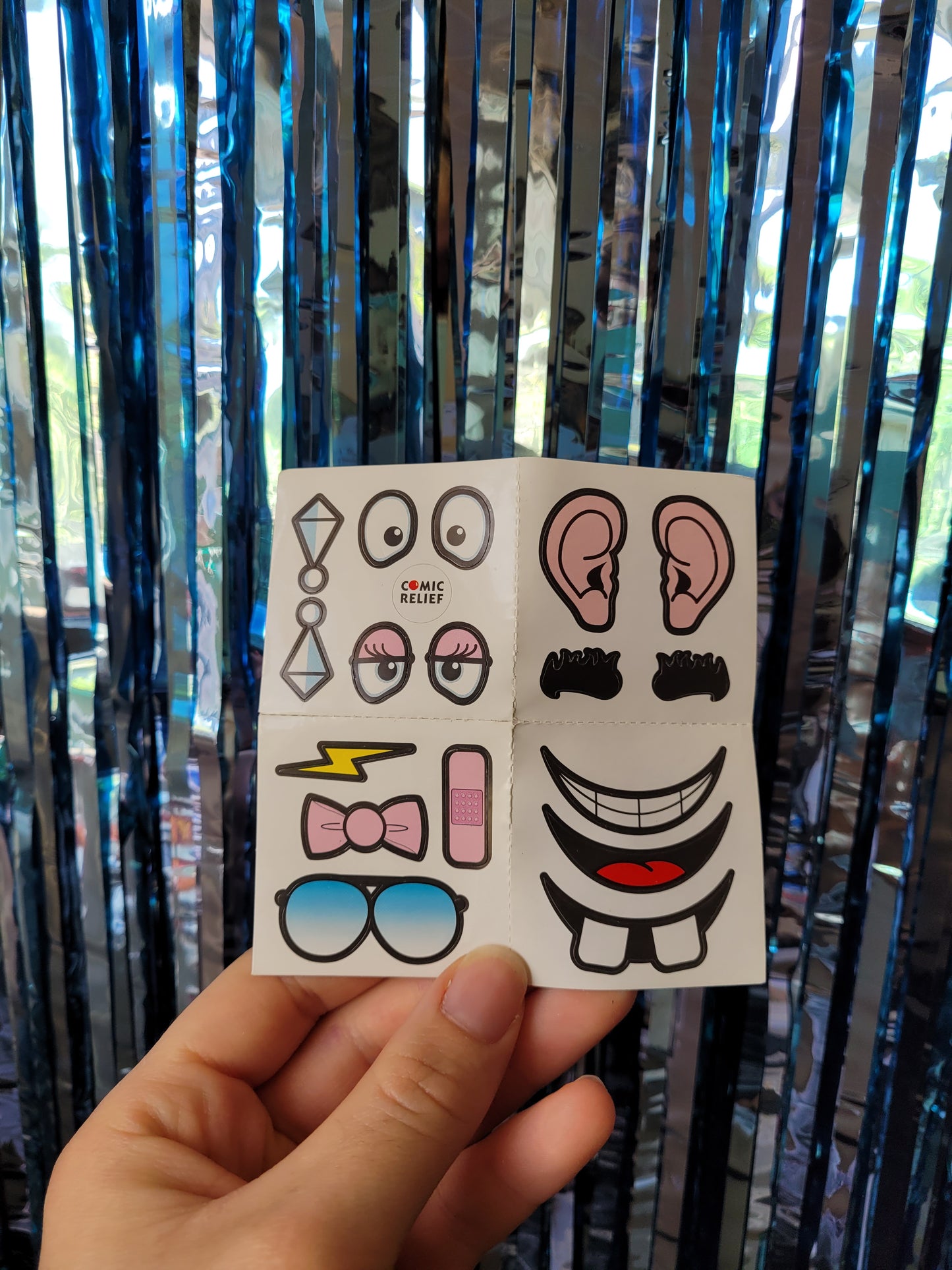 Sheet of stickers including diamond earrings, aviator style sunglasses, a plaster, bushy eyebrows, a bowtie, big ears, different types of smiles and eyes