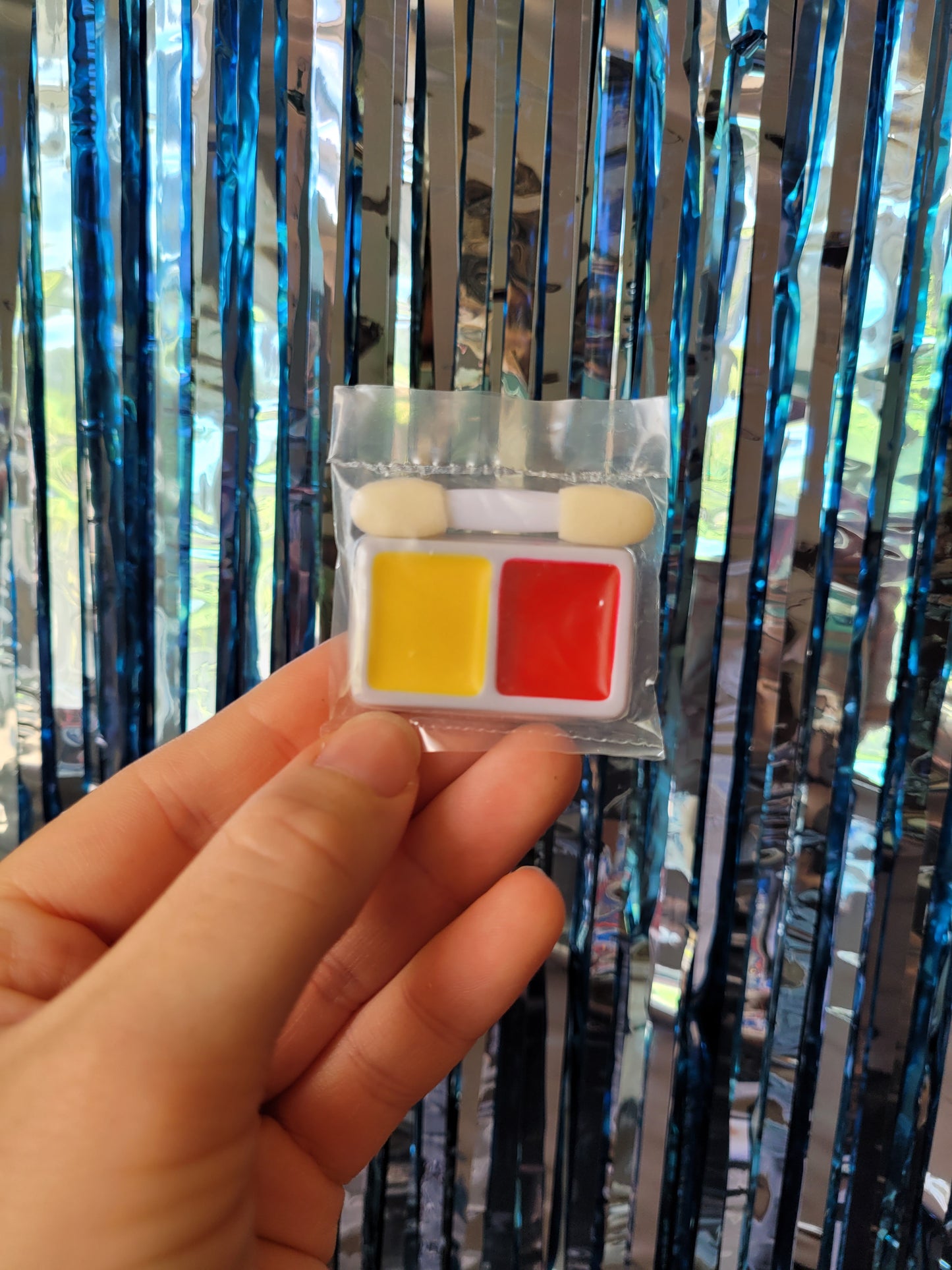 Small palette with red and yellow face paint and cotton bud applicator