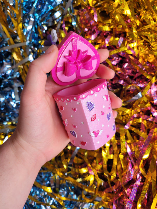 Close up of the bottom of the lid which has a model of a pink ribbon in a bow attached