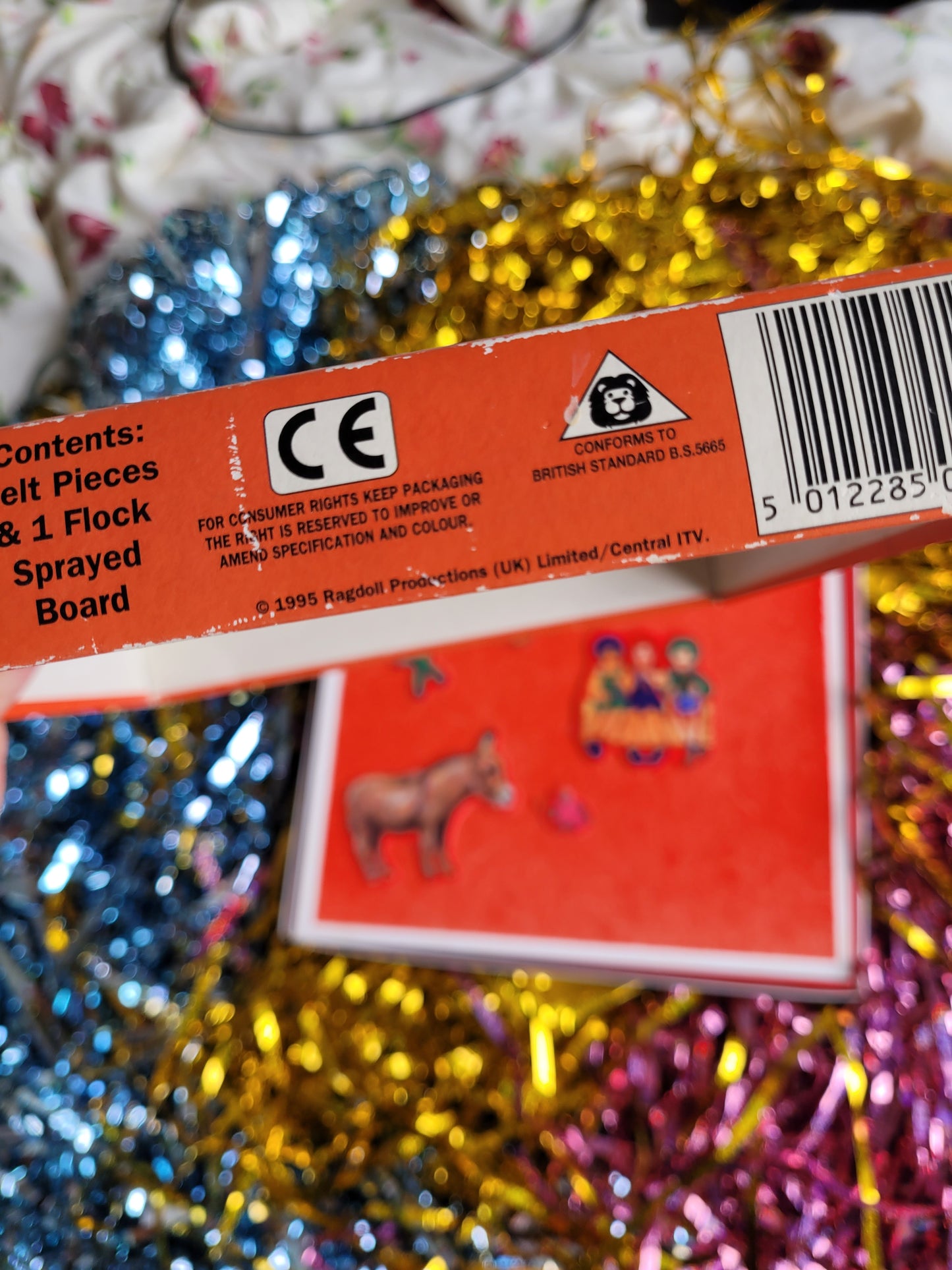 Side of fuzzy felt box reading 1995 against tinsel multicoloured backdrop