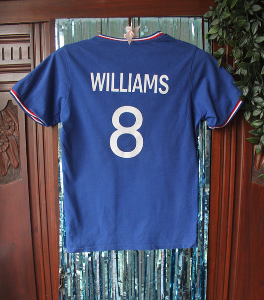 Back of the football shirt with 'Williams' and the number 8 printed in bold white letters. Against a blue sparkly tinsel backdrop.