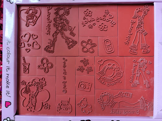 Close up of the red rubber stamps including: 00s style camera, phone and cd player/radio, flowers, butterflies, a teddy, love hearts, a drink with a straw in it, groovy chick in different poses such as waving, lying down, using roller skates and posing with her hand on her hip 