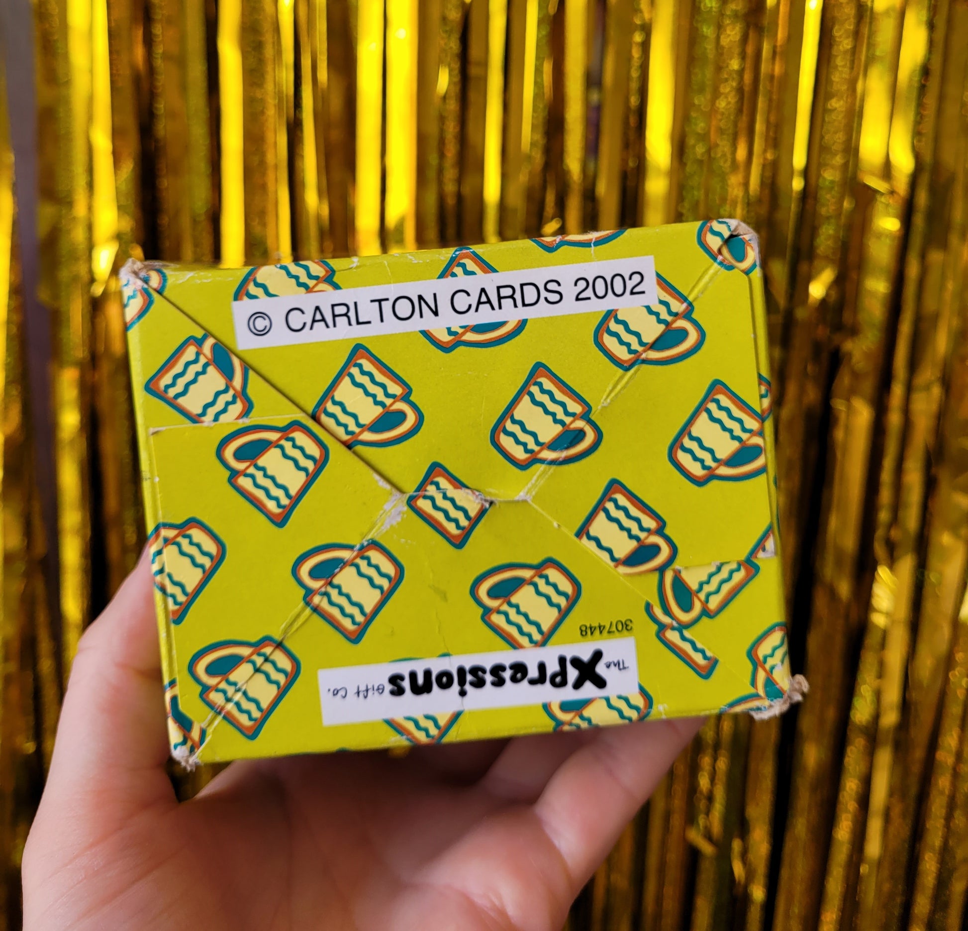 Bottom of the box with a blue and yellow mug pattern. Reads ' Copyright Carlton Cards 2002' 'Xpressions Gift Co.'