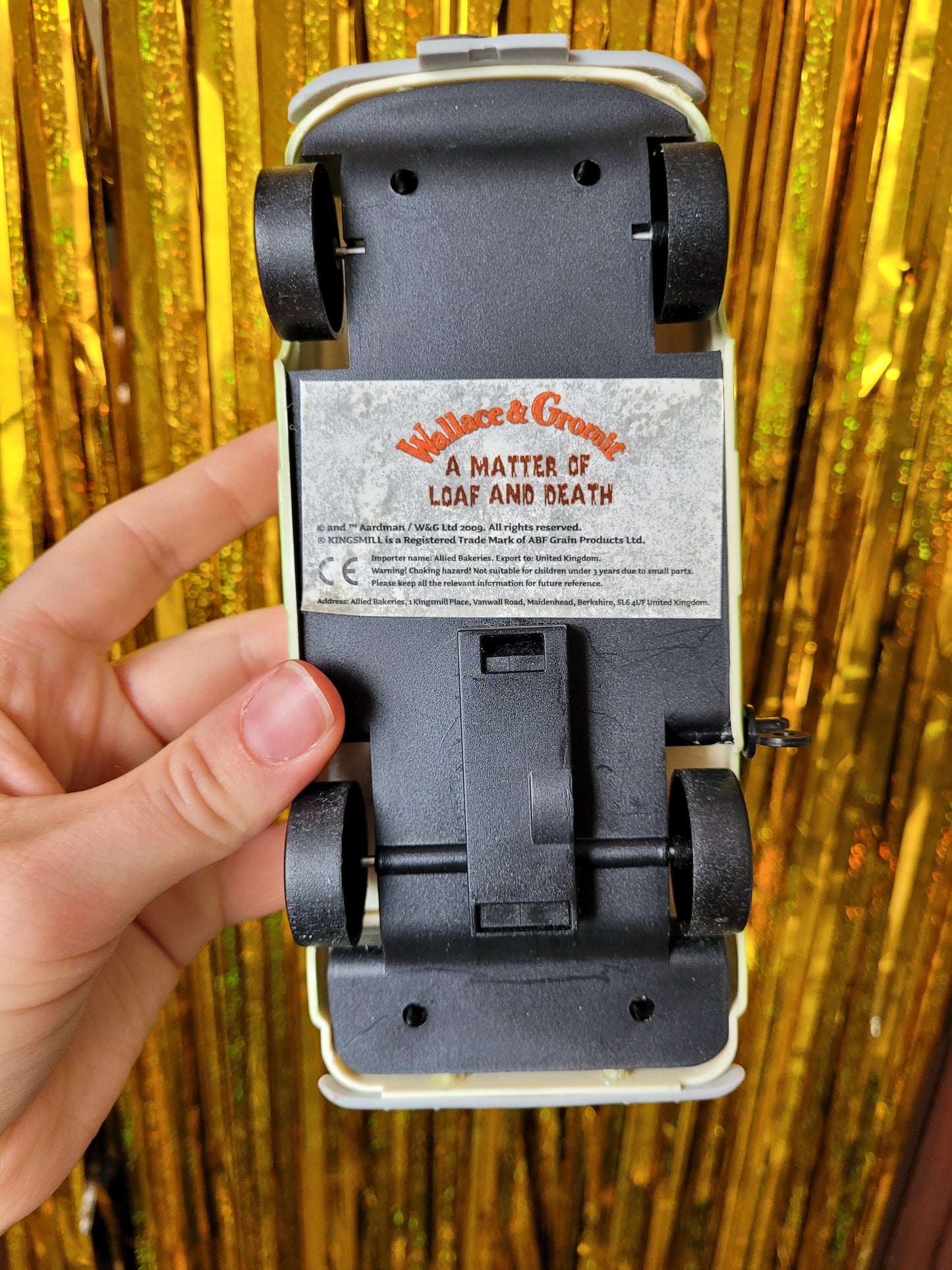 The bottom of the van with a sticker that reads 'Wallace and Gromit' in a fun orange font and 'A Matter of Loaf and Death' in a jokey old school horror style font