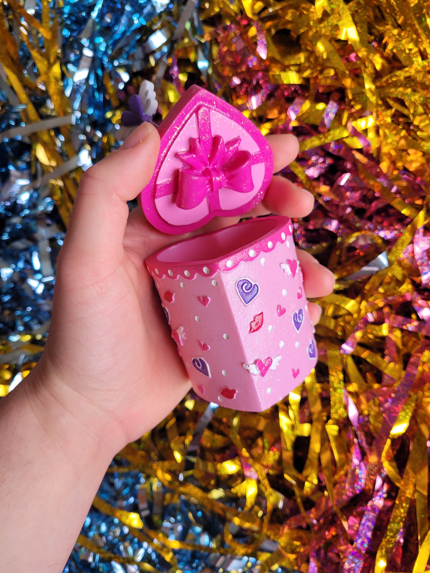 Close up of the bottom of the lid which has a model of a pink ribbon in a bow attached