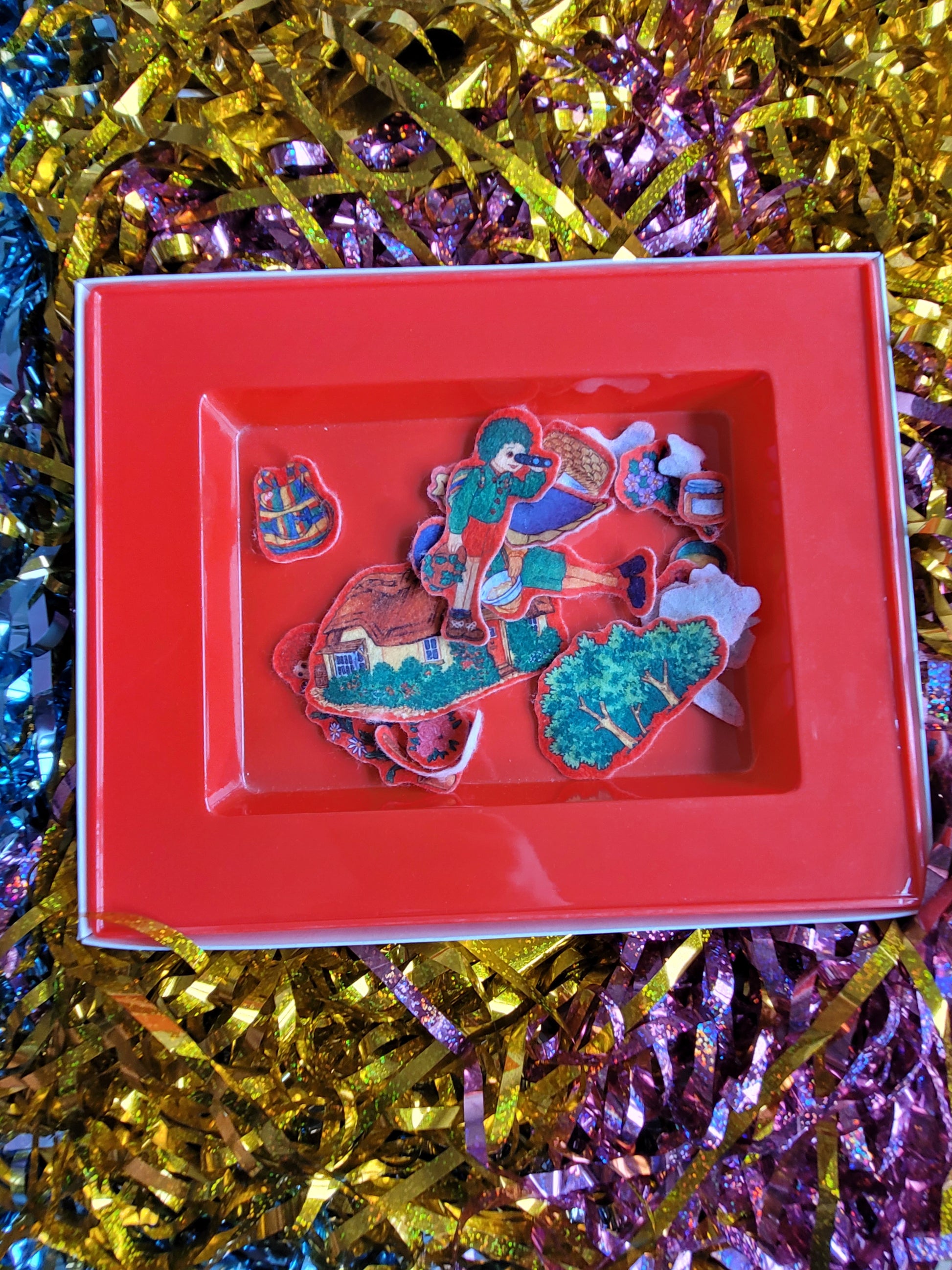 Contents of the fuzzy felt box with colourful tots tv felt pieces inside such as the characters, the house and picnic items