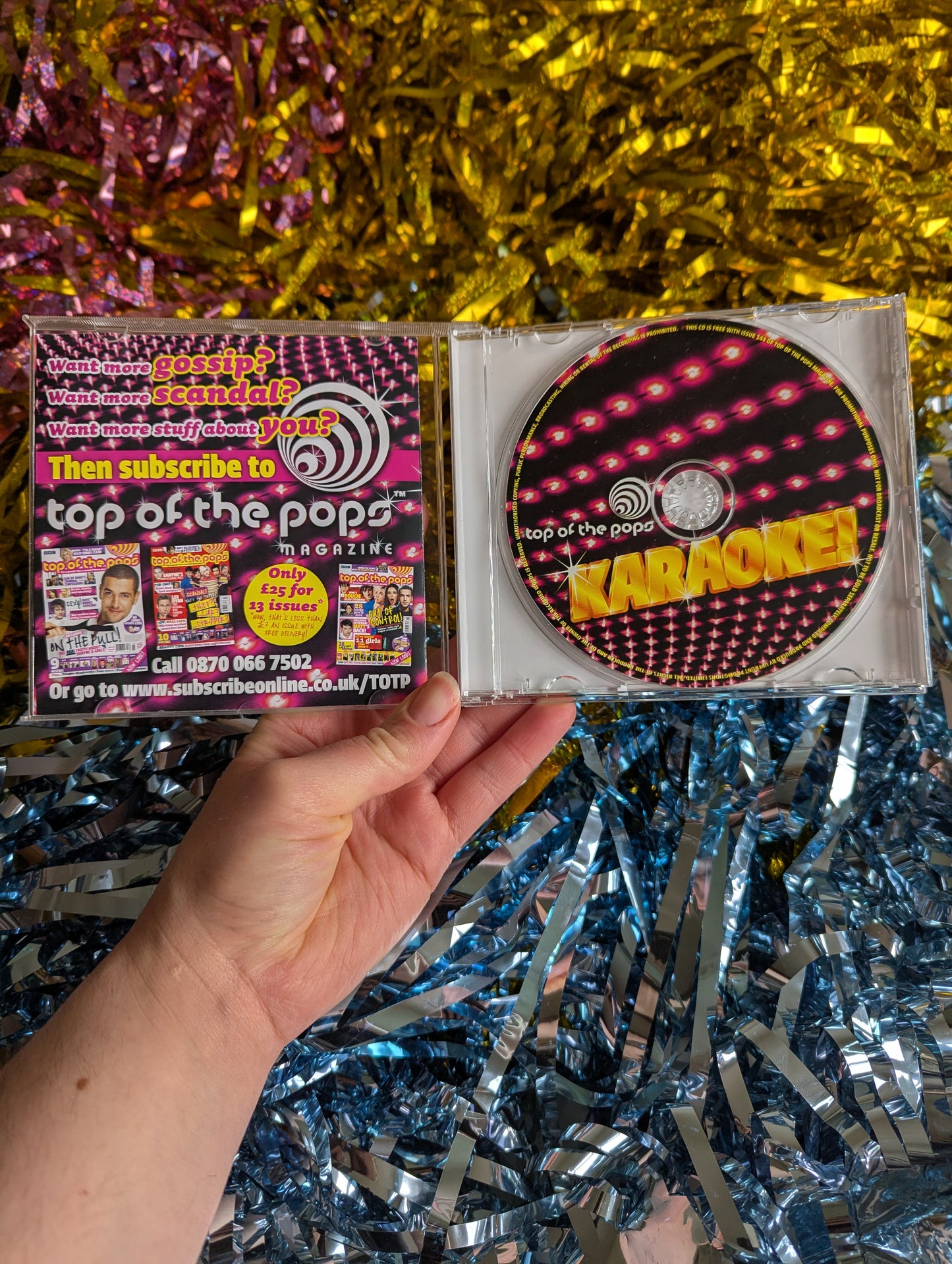 Open cd case with black and pink cd with gold letters 