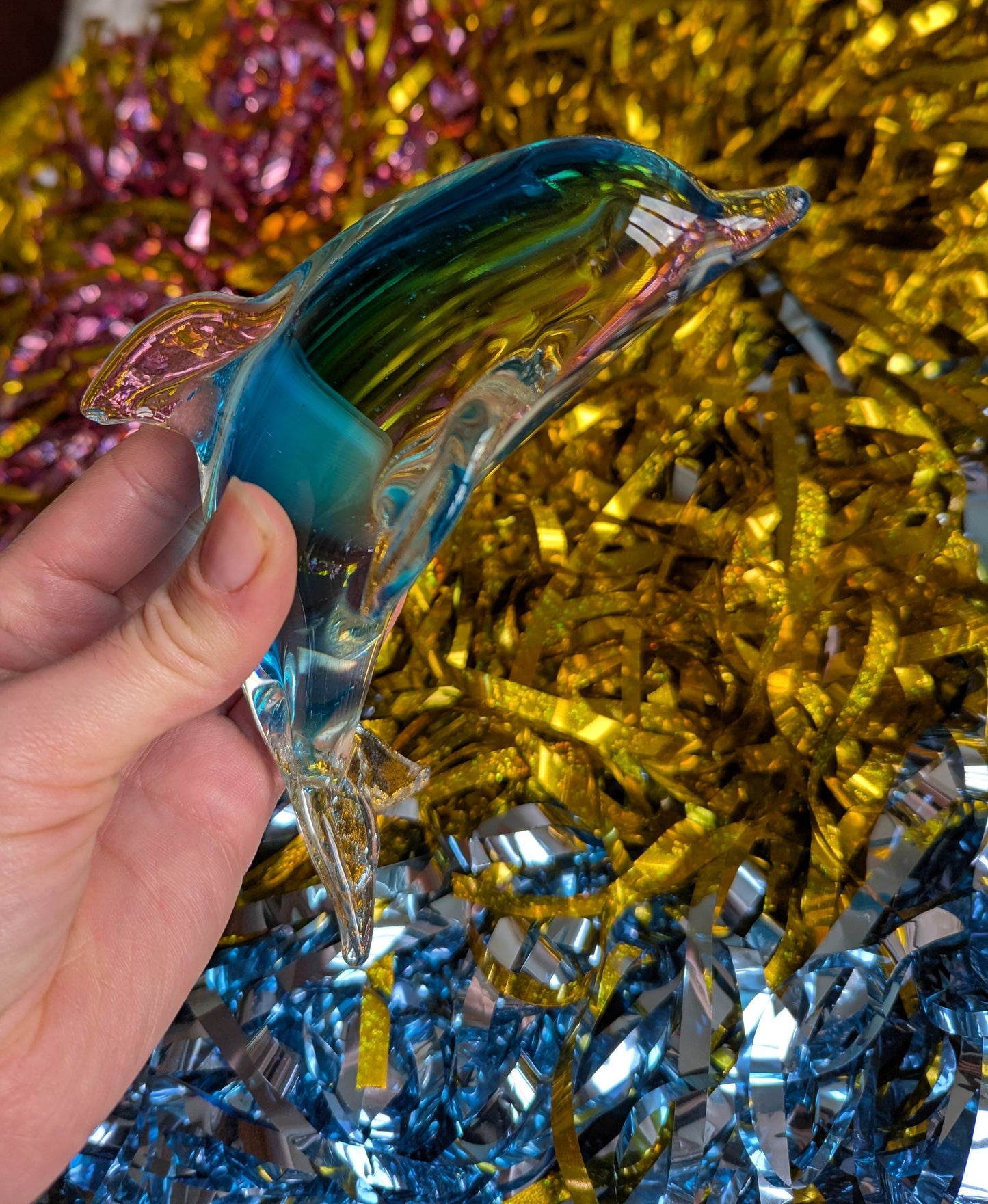 Glass ornament with blue pink and gold tinsel background visible through the glass